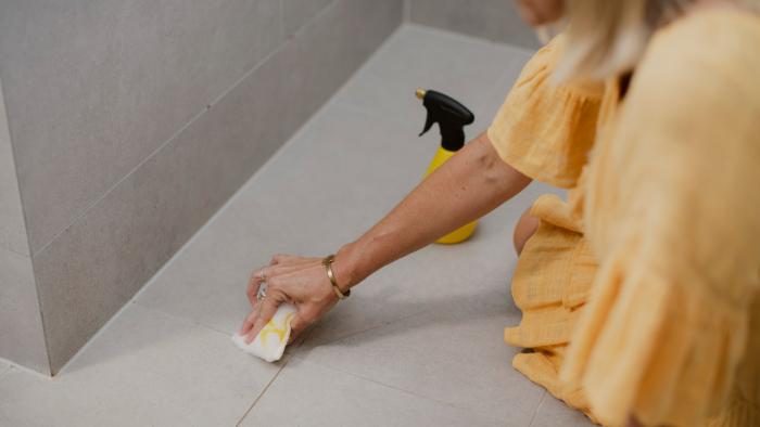 Image of a woman cleaning her bathroom grout with ENJO Australia products.