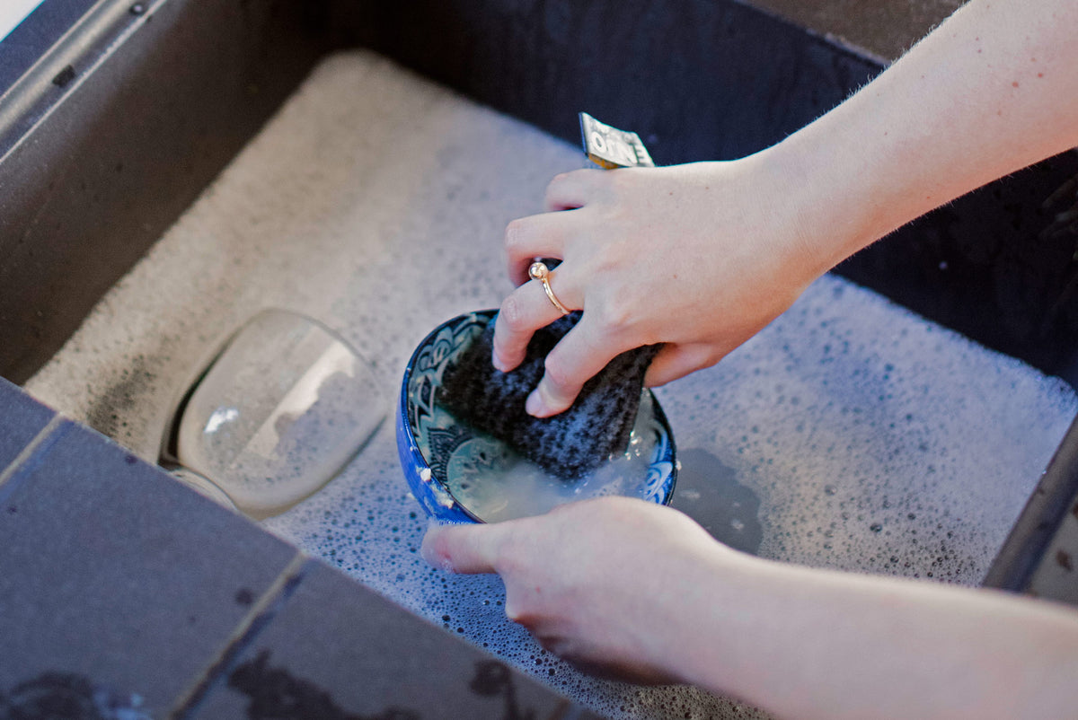 Person cleaning grime from bowl in sink with ENJO Kitchen Sponge