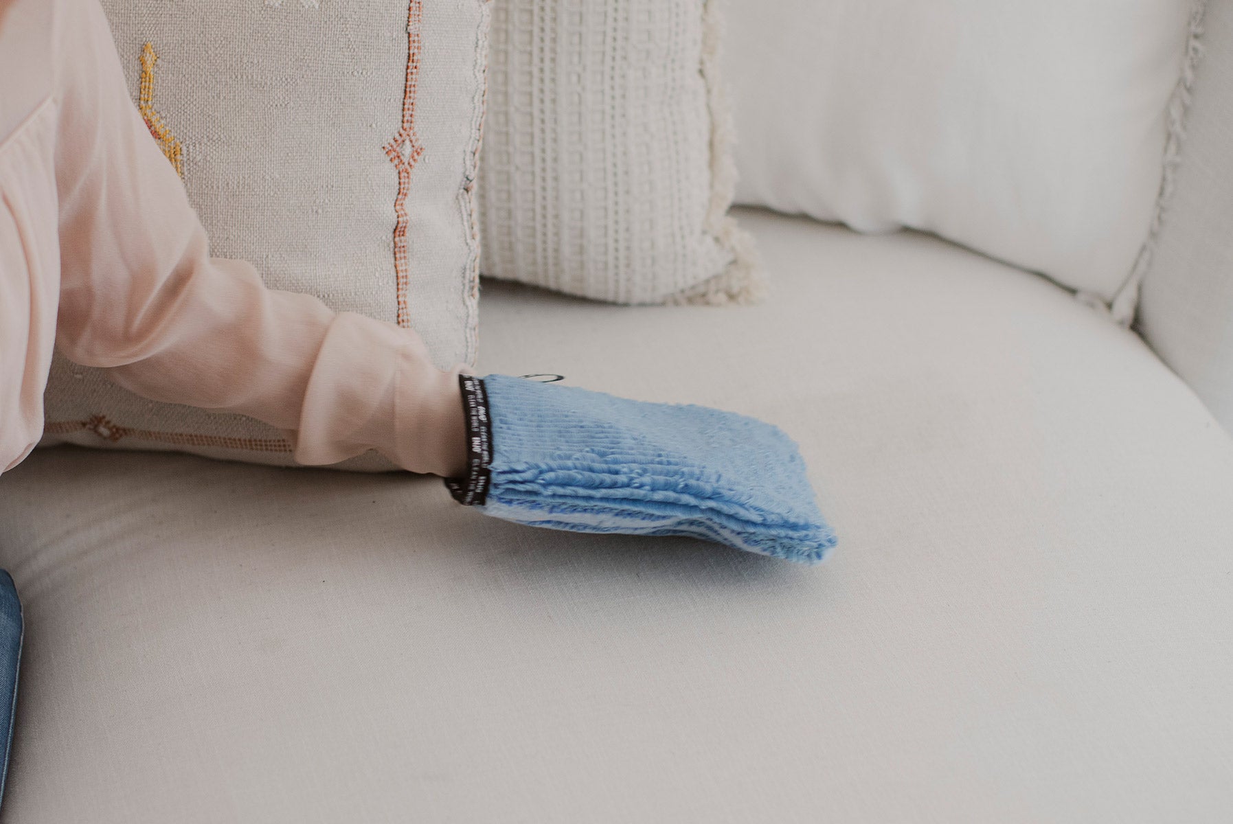 Person removing marks from the couch in the living room with the ENJO Fabric Glove