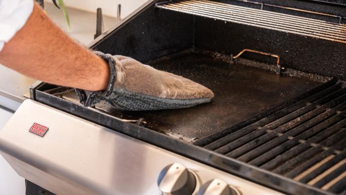 Image of a man cleaning his BBQ with an ENJO outdoor cleaning glove