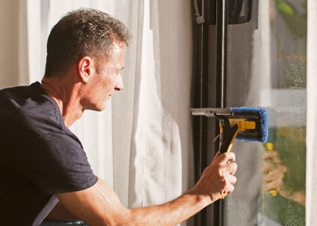 Person cleaning glass door with ENJO Window Multi Tool
