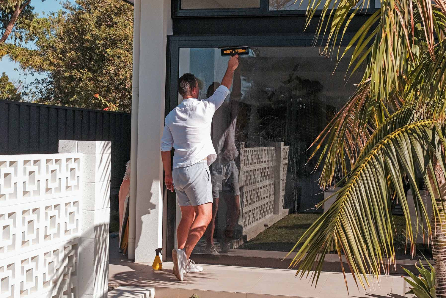 Person cleaning glass door outside with ENJO Window Multi Tool