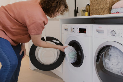 Person putting ENJO Fibres in Medium Laundry Bag ready to wash in washing machine