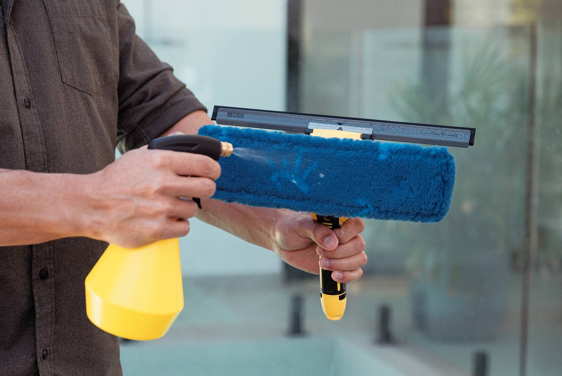 Person spraying water from ENJO Trigger Spray Bottle onto ENJO Window Multi Tool