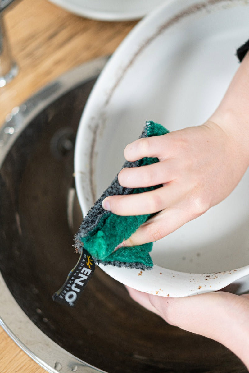 Person cleaning grime from pot with ENJO Kitchen Sponge