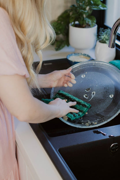 Person cleaning dirty microwave plate with ENJO Kitchen Mini