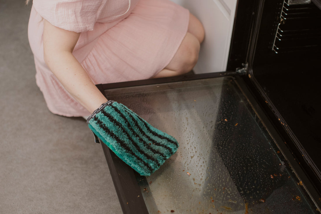 Person cleaning oven door with ENJO Kitchen Glove
