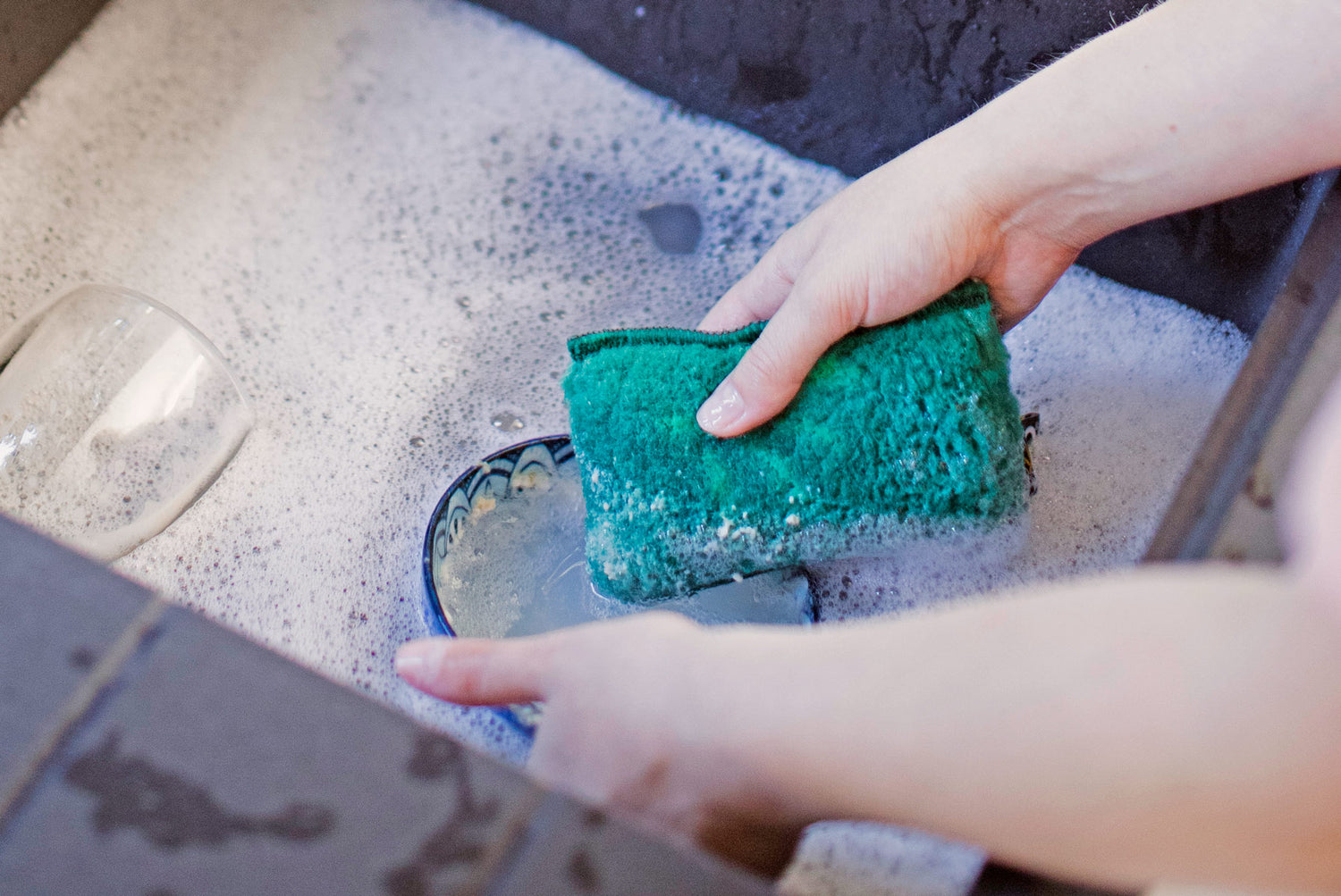 Person cleaning bowl with ENJO Kitchen Sponge in sink