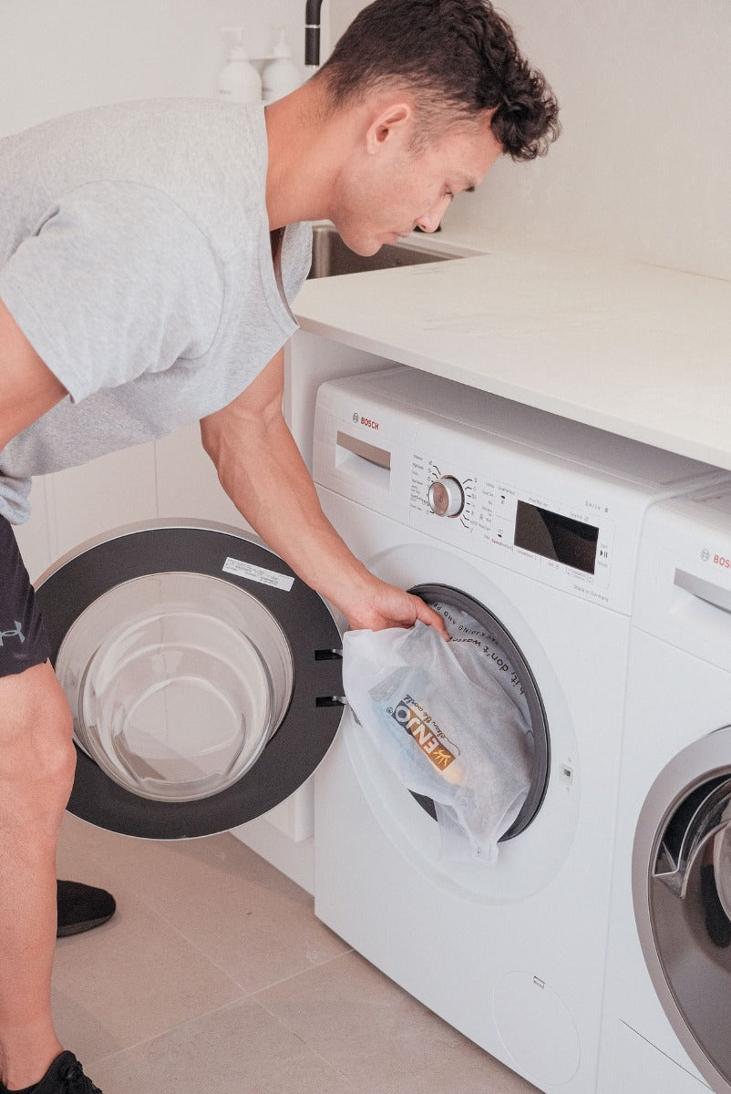 Person putting ENJO Fibres in washing machine