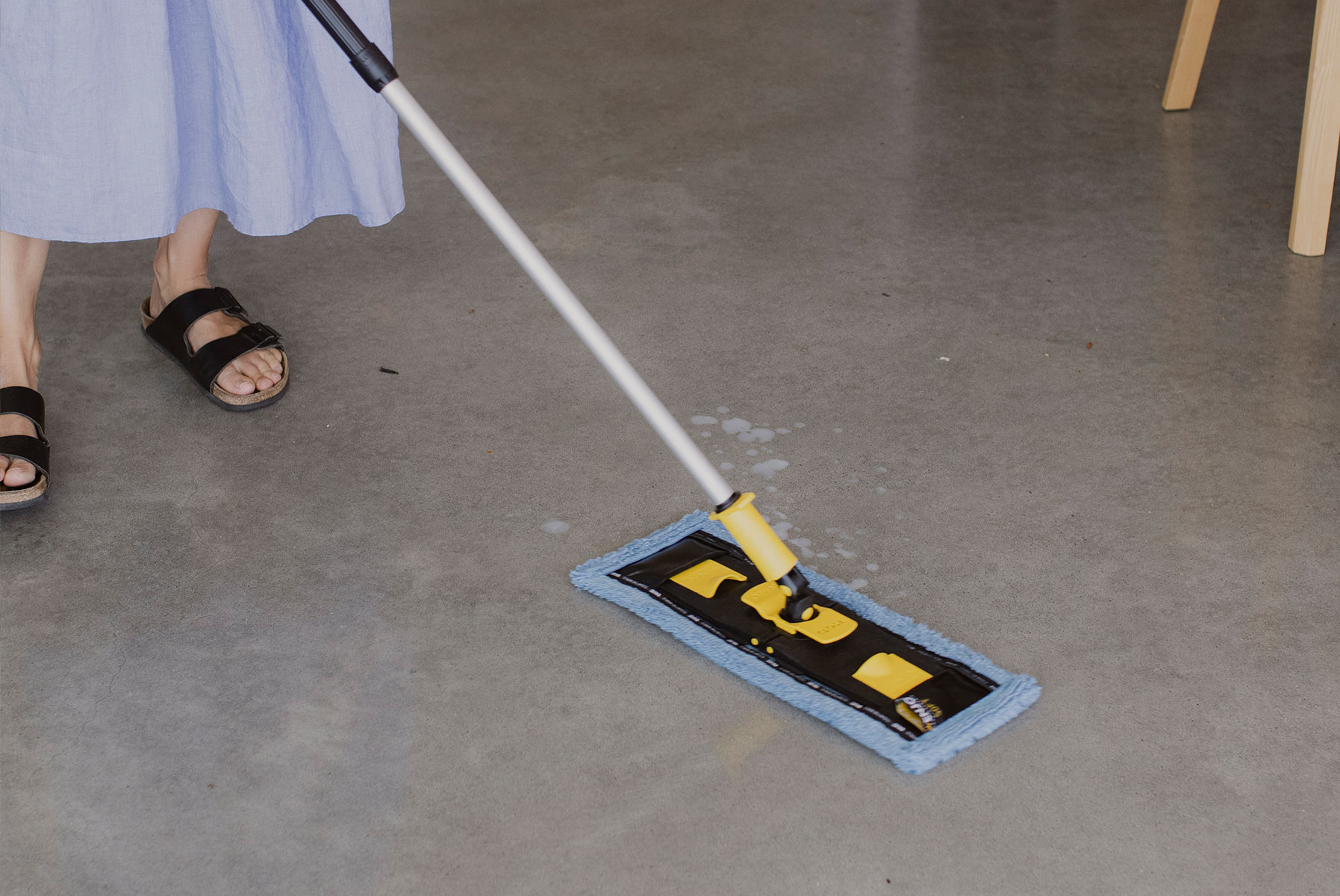 A person cleaning up spilled milk on a polished concrete floor with the ENJO High Gloss Floor Fibre
